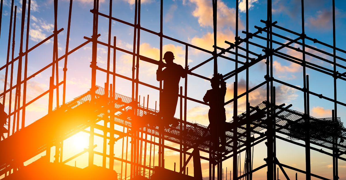 construction workers on scaffolding at sunrise